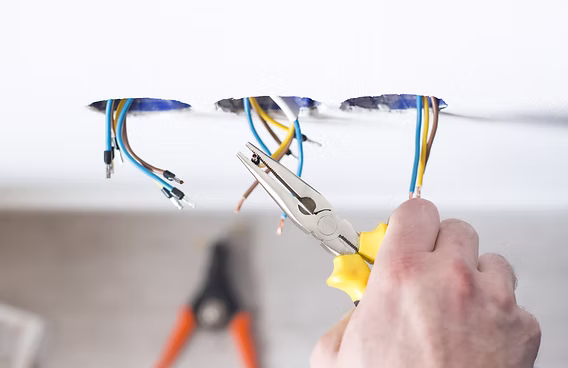 How Much Does It Really Cost to Rewire a House? A Complete Guide to Home Rewiring, Electrical Systems & Hidden Expenses Electrician testing electrical wires with multimeter - house rewiring inspection"
