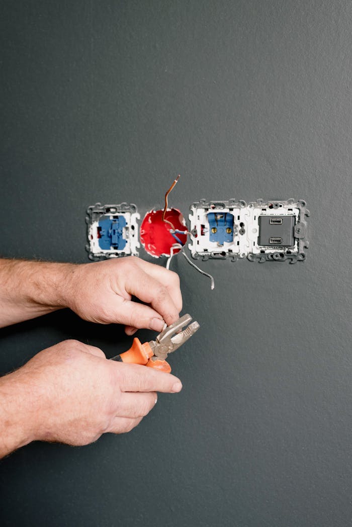 menu-03 Crop faceless electrician using pliers for installation sockets and switches in new apartment